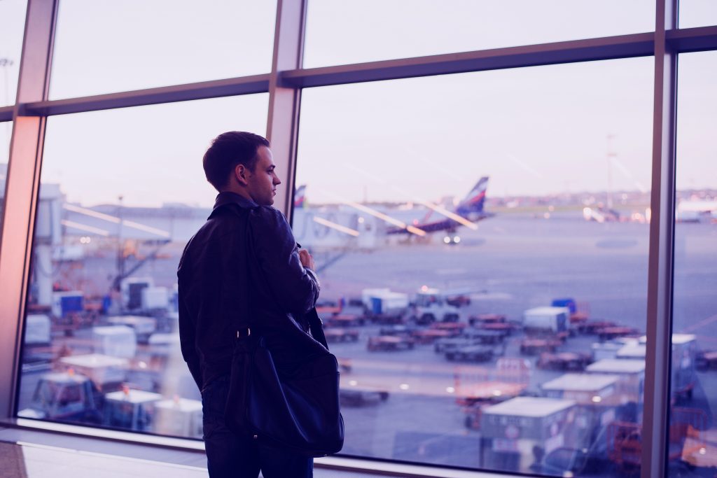 Homem em aeroporto pensando sobre alterar a data do voo!