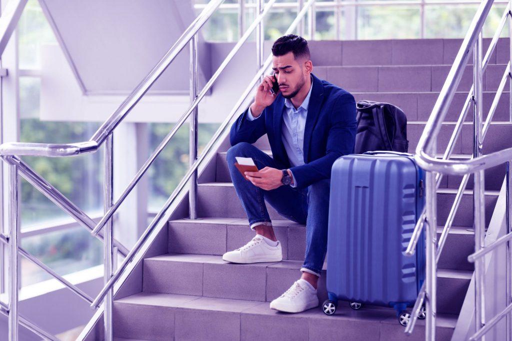 Homem em ligação verificando sobre ação contra companhia aérea por cancelamento de passagem de volta