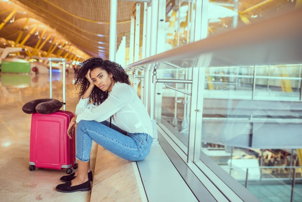 Mulher triste em aeroporto por causa de cancelamento voo Avianca