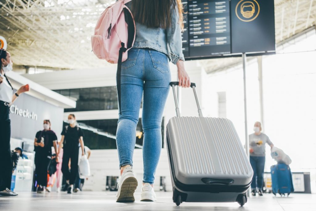 Mulher em aeroporto puxando mala de viagem.