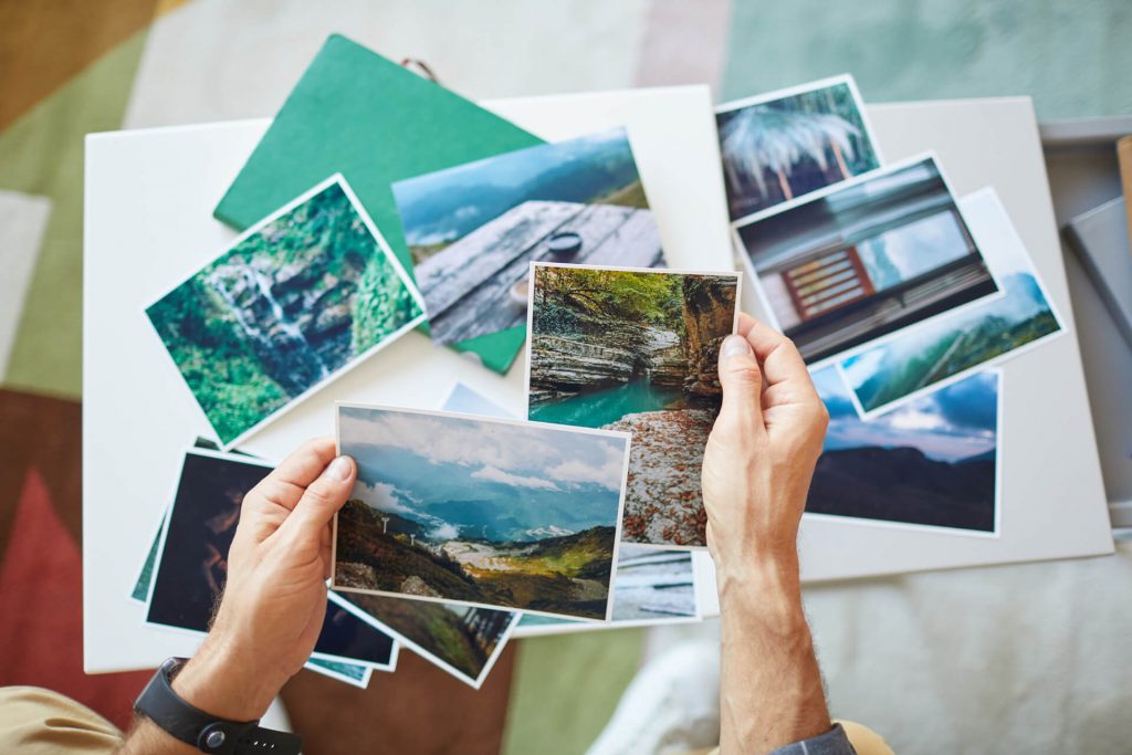 Homem segurando fotos dos destinos internacionais mais procurados para viajar.