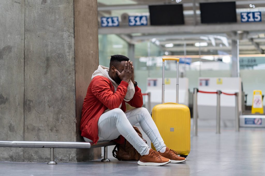 Homem frustrado em aeroporto por causa de alteração de voo pela companhia aérea.