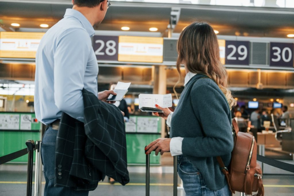 Casal em aeroporto observando se houve taxa abusiva.