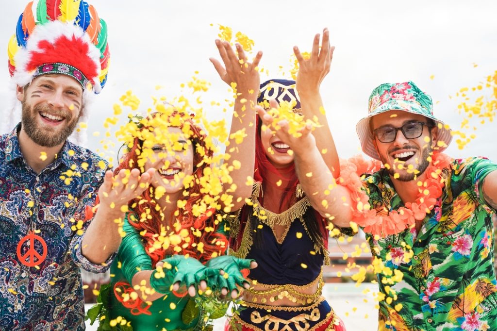 Homens e mulheres curtindo destinos para carnaval, jogando confetes para cima.