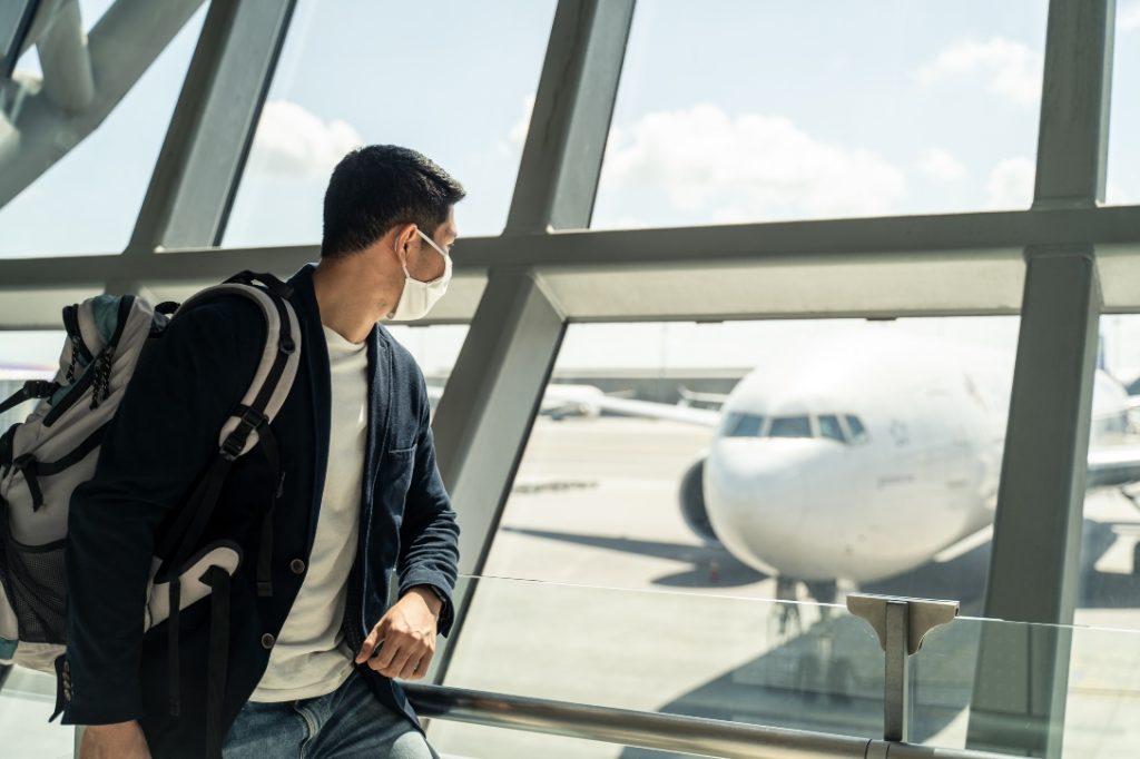 Homem olhando avião partir, devido a overbooking e direito do consumidor não foi considerado.