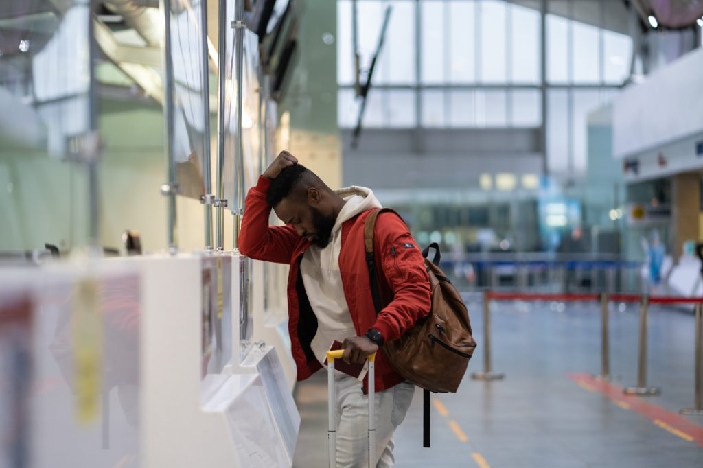 Homem em guichê de aeroporto, com problema de voo.