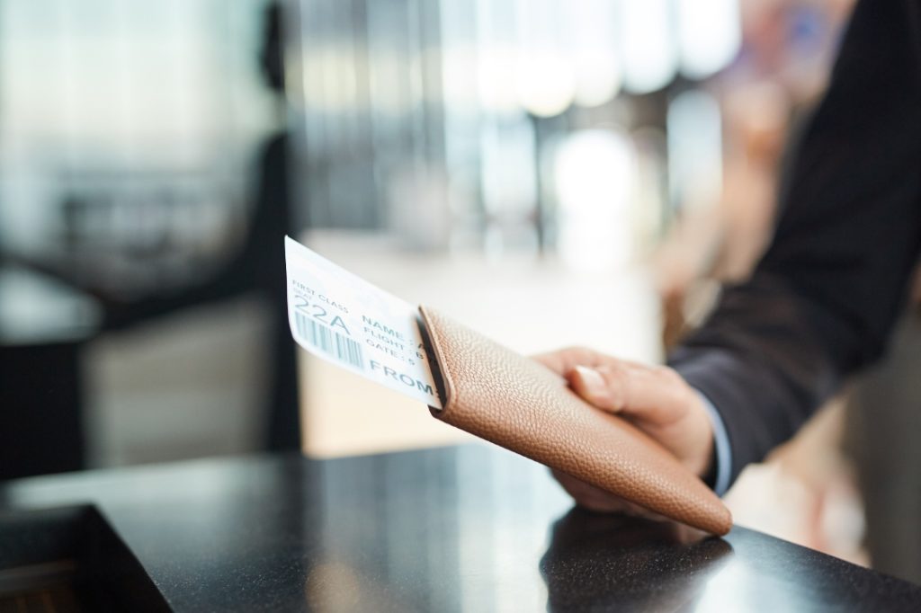 Homem com bilhete na mão para cancelar passagem aérea.