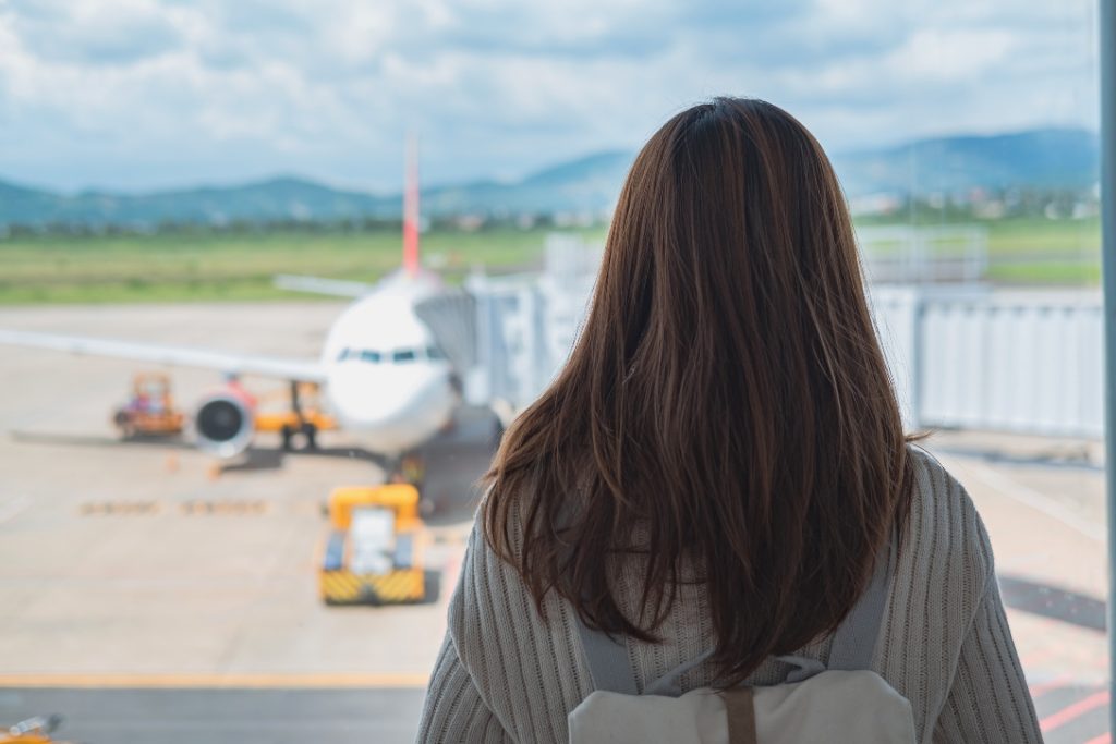 Mulher observando aviões enquanto passa por cancelamentos de voos.